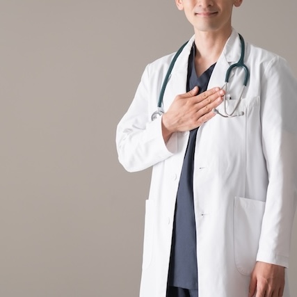 胸に手を当てる白衣の医師 | 歯科コンサル.com